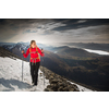 Pretty, young female hiker going uphill with splendid hills around her