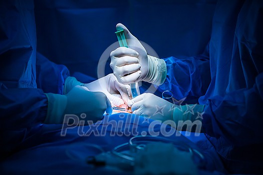 Surgery in a modern hospital being performed by a team of professionals (shallow DOF, color toned image) Surgery in a modern hospital being performed by a team of professionals (shallow DOF, color toned image)