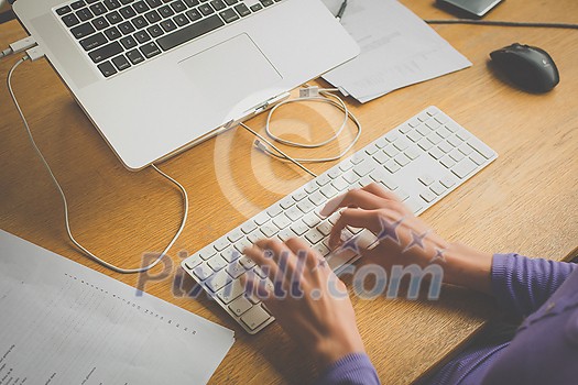 Hands of a young woman working on a computer at an office