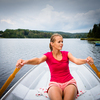 Happy, young woman enjoying rowing boat ride on a lake on a summer day