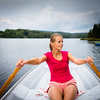 Happy, young woman enjoying rowing boat ride on a lake on a summer day
