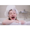 little girl playing with soap foam in bath during coronavirus stay at home pandemic quarantine