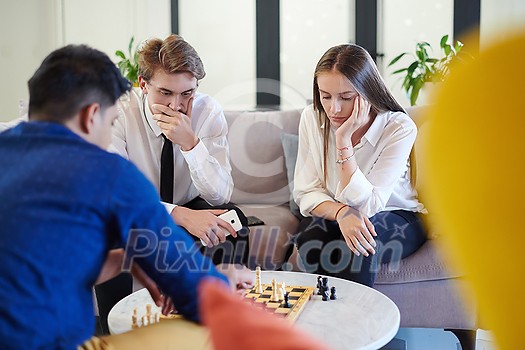 multiethnic group of business people playing chess while having a break in relaxation area at modern startup office multiethnic group of business people playing chess while having a break in relaxation area at modern startup office