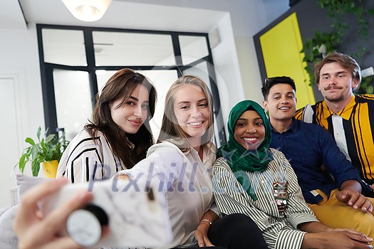 group of casual multiethnic business people during break from the work taking selfie picture while enjoying free time in relaxation area at modern open plan startup office