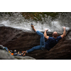 A rock climber climbing on a boulder rock outdoors. Group of friends involved in sports outside.