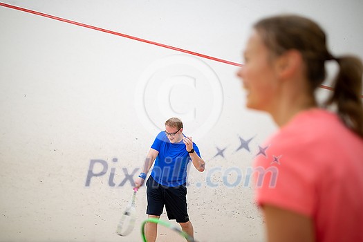Squash players in action on a squash court (motion blurred image; color toned image) Squash players in action on a squash court (motion blurred image; color toned image)