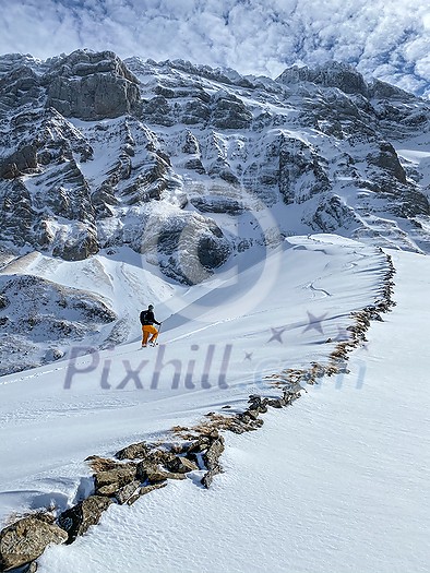 Winter sports - young man walking with snowshoes uphill in high mountains covered with lots of snow