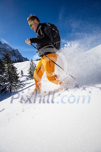 Winter sports - young man running with snowshoes downhill in high mountains covered with lots of snow Winter sports - young man running with snowshoes downhill in high mountains covered with lots of snow