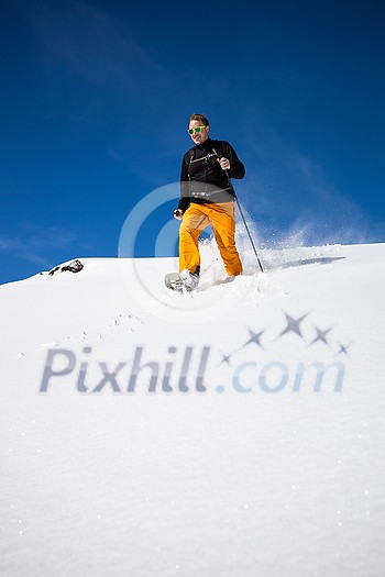 Winter sports - young man running with snowshoes downhill in high mountains covered with lots of snow Winter sports - young man running with snowshoes downhill in high mountains covered with lots of snow