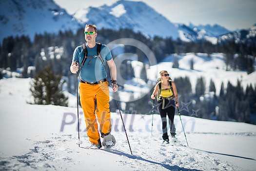 Winter sports - two friends hiking with snowshoes in high mountains