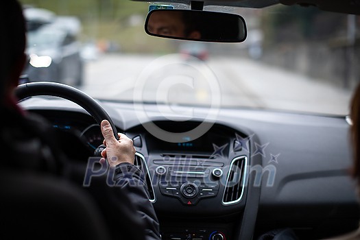 Driver's hands on a steering wheel of a car and blue sky with blurred clouds Driver's hands on a steering wheel of a car and blue sky with blurred clouds