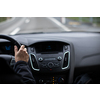 Driver's hands on a steering wheel of a car and blue sky with blurred clouds