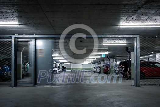 Gated underground parking. Cars parked in a garage with no people. Many cars in parking garage interior. Underground parking with cars (color toned image) Gated underground parking. Cars parked in a garage with no people. Many cars in parking garage interior. Underground parking with cars (color toned image)