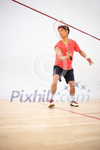 Squash player in action on a squash court (motion blurred image; color toned image)