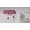 A glass with mix berries and milk. A plate filled raspberries, blueberries, cherries on a white table. The focus changes from the plate to the glass. Shallow depth of field. Slow motion video, 4K.