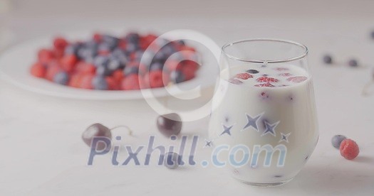 A glass with mix berries and milk. A plate filled raspberries, blueberries, cherries on a white table. The focus changes from the glass to the plate. Shallow depth of field. Slow motion video, 4K. A glass with mix berries and milk. A plate filled raspberries, blueberries, cherries on a white table. The focus changes from the glass to the plate. Shallow depth of field. Slow motion video, 4K.