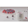A glass with mix berries and milk. A plate filled raspberries, blueberries, cherries on a white table. The focus changes from the glass to the plate. Shallow depth of field. Slow motion video, 4K.