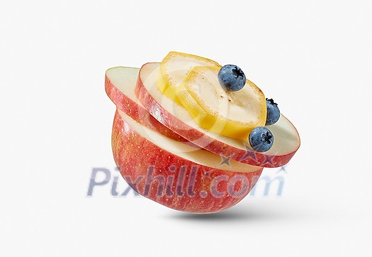 Close-up view of fresh ripe organic natural apple with slices of banana and blueberries on a white background wih soft shadows, copy space. Vegan healthy food concept.