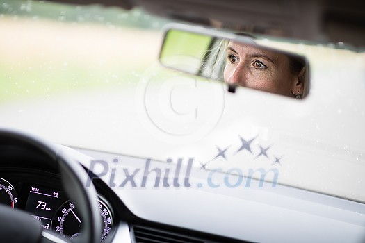 Pretty midle aged woman at the steering wheel of her car commuting to work