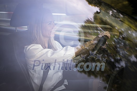 Pretty middle aged woman at the steering wheel of her car