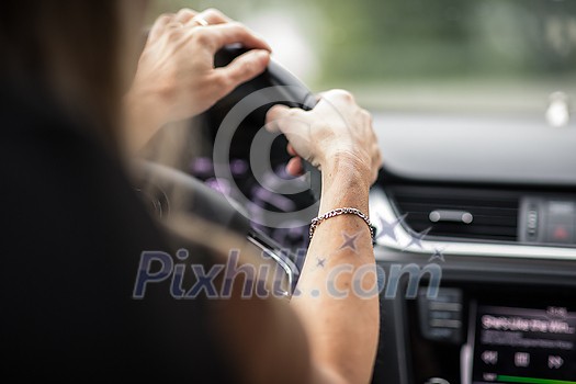 Pretty midle aged woman at the steering wheel of her car commuting to work