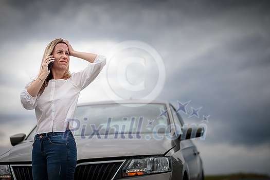 Pretty middle aged woman having car troubles - broken down car on the side of the road, calling the insurance company for assistance Pretty middle aged woman having car troubles - broken down car on the side of the road, calling the insurance company for assistance