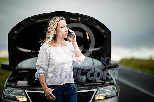 Pretty middle aged woman having car troubles - broken down car on the side of the road, calling the insurance company for assistance Pretty middle aged woman having car troubles - broken down car on the side of the road, calling the insurance company for assistance