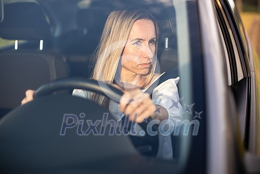 Pretty middle aged woman at the steering wheel of her car