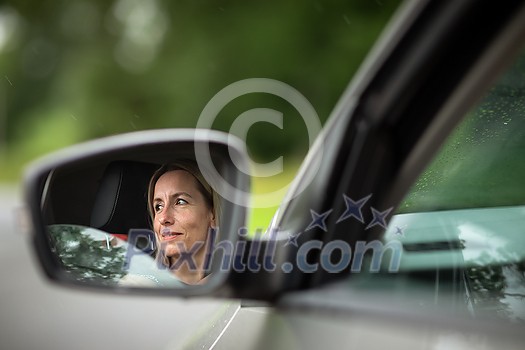 Pretty midle aged woman at the steering wheel of her car commuting to work