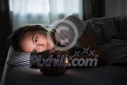 Pretty, young woman sleeping in her bed with her cell phone close to her. Smartphone in Bed Mobile/smartphone  Addiction Concept.