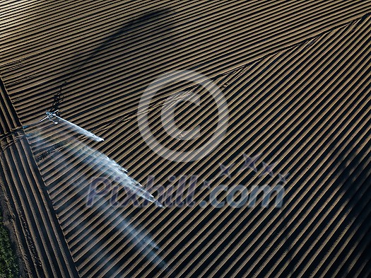 Intense agriculture fiekd being irrigatedwith huge amounts of water on a hot summer day - aerial image Intense agriculture fiekd being irrigatedwith huge amounts of water on a hot summer day - aerial image