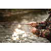 Close-up view of the hands of a fly fisherman working the line and the fishing rod while fly fishing on a splendid mountain river for rainbow trout