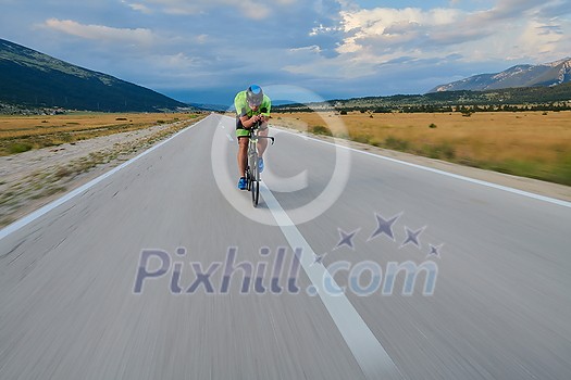 triathlon athlete riding professional racing bike at workout on curvy country road