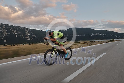 triathlon athlete riding professional racing bike at workout on curvy country road