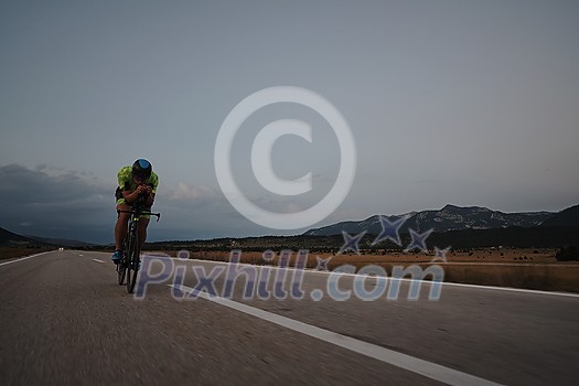 triathlon athlete riding professional racing bike at workout on curvy country road