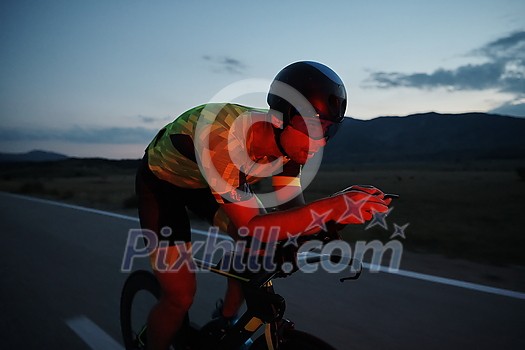 triathlon athlete riding professional racing bike at night workout on curvy country road w triathlon athlete riding professional racing bike at night workout on curvy country road w