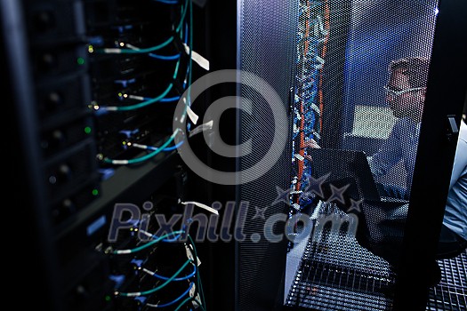 Data center employee running tests on the server computers, dealing with an urgent issue, security breach, updateing the system (color toned image) Data center employee running tests on the server computers, dealing with an urgent issue, security breach, updateing the system (color toned image)
