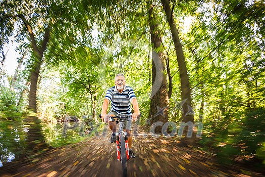 Senior man going fast on his bike during his regular afternoon ride - enjoying actively his retirement - motion blur used to convey speed and movement Senior man going fast on his bike during his regular afternoon ride - enjoying actively his retirement - motion blur used to convey speed and movement