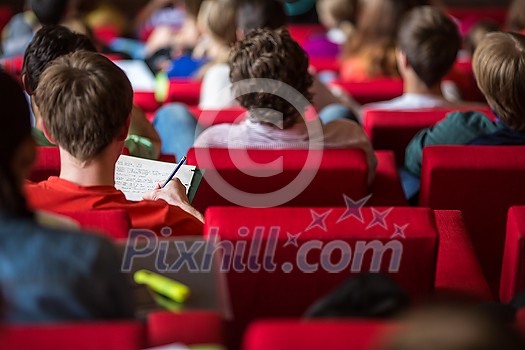 University students sitting in class, taking notes University students sitting in class, taking notes