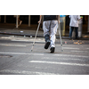 Man with crutches crossing a street