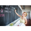 Pretty young teacher writing on the chalkboard/blackboard during class (shallow DOF; color toned image)