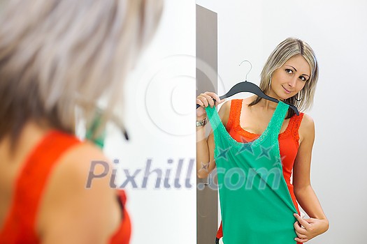 Young woman shopping in a fashion store - Trying on the garments she likes (color toned image; shallow DOF) Young woman shopping in a fashion store - Trying on the garments she likes (color toned image; shallow DOF)