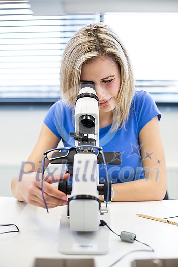Pretty, female optometrist measuring newly made glasses - veryfing it is spot on