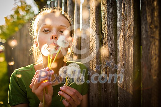 Portrait of happy young woman relaxing on a lovely summer day,  playing with dandelions