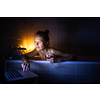 Young woman taking a bath, drinking red wine, enjoying a movie, relaxing after busy work day