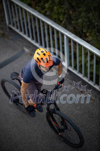 Cross country mtb biker going for his favorite hills beyond the city limits (top view; shallow DOF) Cross country mtb biker going for his favorite hills beyond the city limits (top view; shallow DOF)