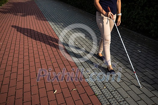 Blind woman walking on city streets, using her white cane Blind woman walking on city streets, using her white cane