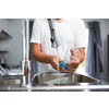 Senior man washing dishes in his modern, bright kitchen (shallow DOF; color toned image)