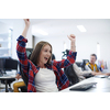 happy casual business woman celebrating success while working on desktop computer in modern open plan startup office interior