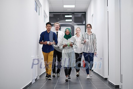 multi-ethnic startup business team walking through the hallway of the building while coming back from a coffee break